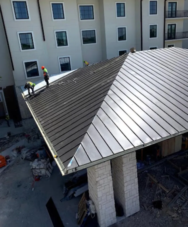 Crew installing standing seam metal roof panels on a commercial project in Winthrop Harbor